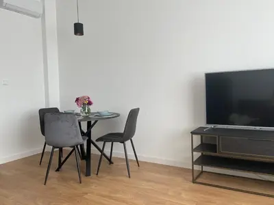 a dining room with a table and chairs and a tv at Apartament Oboźna in Kraków