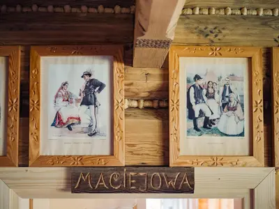 a group of framed pictures on a wooden wall at Apartamenty Przystań 18 Gorce w Rabce Zdrój in Rabka