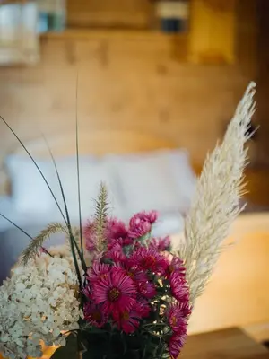 a vase of flowers on a table with a bed at Apartamenty Przystań 18 Gorce w Rabce Zdrój in Rabka