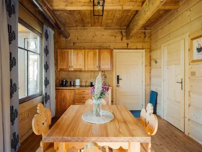 a dining room with a wooden table with flowers on it at Apartamenty Przystań 18 Gorce w Rabce Zdrój in Rabka