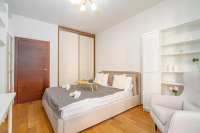 a white bedroom with a bed and a chair at Rakowicka Residence Parking Balkon By Hosty in Kraków