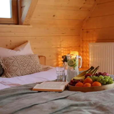 a tray of fruit on a bed with a book at Leśny Zakątek Zawoja in Stryszawa