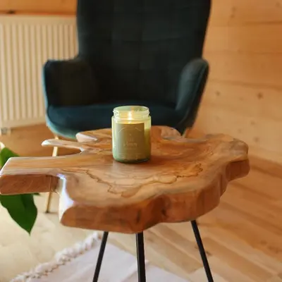a candle on a wooden table with a chair at Leśny Zakątek Zawoja in Stryszawa