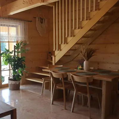 a dining room with wooden tables and chairs and stairs at Leśny Zakątek Zawoja in Stryszawa