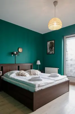 a bedroom with a large bed with a green wall at Walerego Sławka Apartament in Kraków