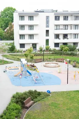 a playground in front of a large white building at Walerego Sławka Apartament in Kraków