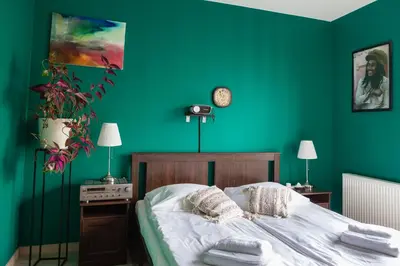 a bedroom with green walls and a bed with white sheets at Walerego Sławka Apartament in Kraków