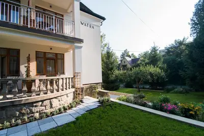 a white house with a balcony and a yard at Apartamenty Watra in Rabka