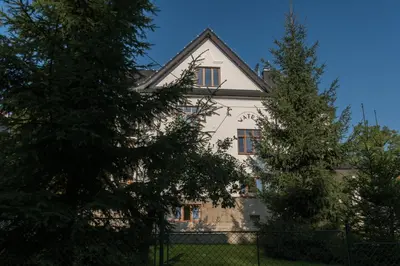 a white house with a tree in front of it at Apartamenty Watra in Rabka