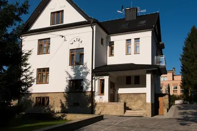 a white house with a black roof at Apartamenty Watra in Rabka