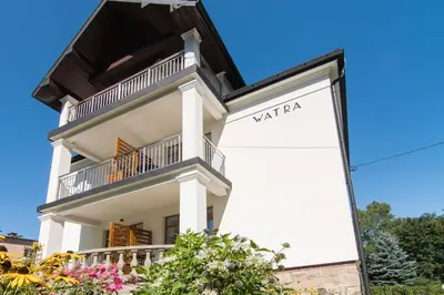 a white house with a sign in front of it at Apartamenty Watra in Rabka