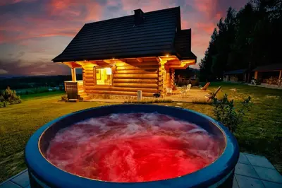 a hot tub in front of a log cabin at Góralski dom balia kominek Lawendowy Dom na Wichrowym Wzgórzu in Łętownia Dolna