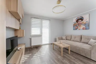 a living room with a couch and a table at Osiedle Piastów Charming Apartment by BookingHost in Kraków