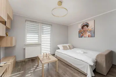 a white bedroom with a bed and a table at Osiedle Piastów Charming Apartment by BookingHost in Kraków