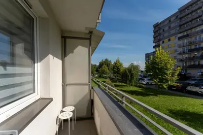 a balcony with two chairs and a window at Osiedle Piastów Charming Apartment by BookingHost in Kraków