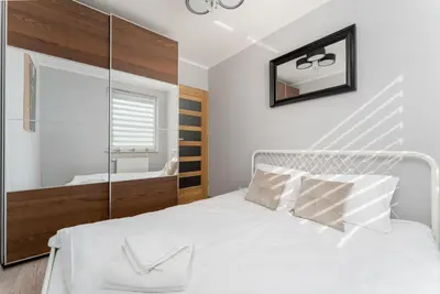 a bedroom with a white bed and a mirror at Osiedle Piastów Charming Apartment by BookingHost in Kraków