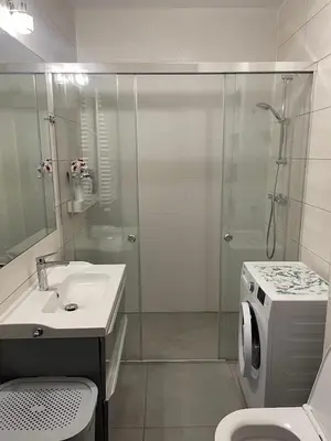 a bathroom with a shower and a sink and a washing machine at Apart Wielicka 57 in Kraków