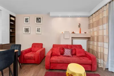 a living room with a red couch and a chair at Łagiewniki Homely Apartment by BookingHost in Kraków