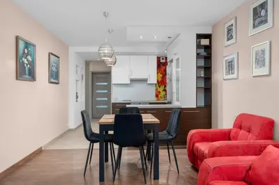 a living room with a table and a red couch at Łagiewniki Homely Apartment by BookingHost in Kraków