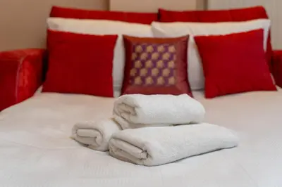 a pile of towels on a bed with red pillows at Łagiewniki Homely Apartment by BookingHost in Kraków