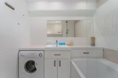 a white bathroom with a washing machine and a sink at Łagiewniki Homely Apartment by BookingHost in Kraków
