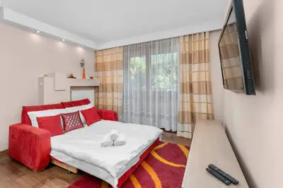 a bedroom with a red bed and a flat screen tv at Łagiewniki Homely Apartment by BookingHost in Kraków