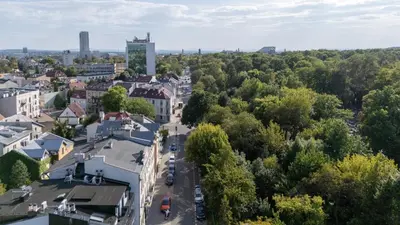 a woman walking down a street next to a building at Rakowicka Superior Studio by BookingHost in Kraków