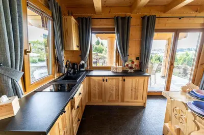 a kitchen with wooden cabinets and a large window at Babi czas in Podsarnie