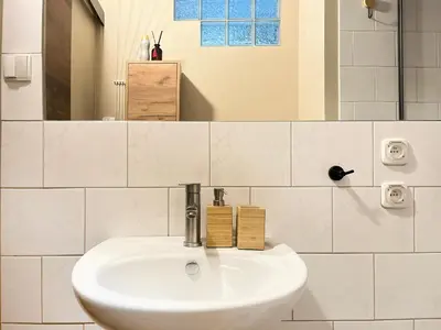 a white sink in a white tiled bathroom at Cozy Apartment Inspiro, Cracow Old Town in Kraków