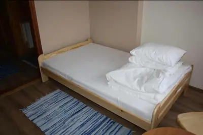 a small bed with white sheets and pillows on it at Noclegi KLARA in Zawoja