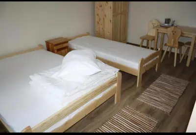 two beds in a room with a table and chairs at Noclegi KLARA in Zawoja