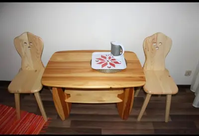 a wooden table with two chairs and a mug on it at Noclegi KLARA in Zawoja