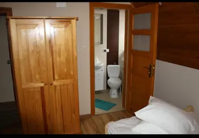 a bedroom with a bathroom with a toilet and a door at Noclegi KLARA in Zawoja