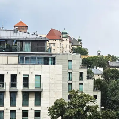 a tall white building in front of a city at Juwel Apartments z widokiem na Wawel 32 in Kraków