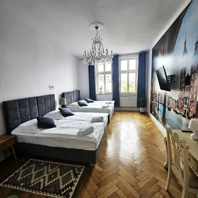 a bedroom with three beds and a chandelier at Juwel Apartments z widokiem na Wawel 32 in Kraków