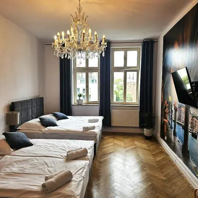a room with three beds and a chandelier at Juwel Apartments z widokiem na Wawel 32 in Kraków