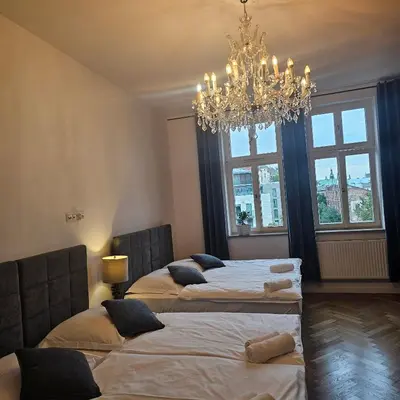 a bedroom with three beds and a chandelier at Juwel Apartments z widokiem na Wawel 32 in Kraków