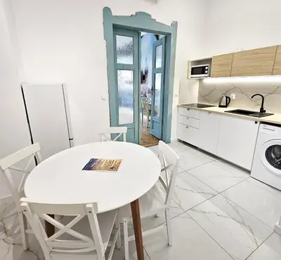 a white kitchen with a white table and chairs at Juwel Apartments z widokiem na Wawel 32 in Kraków
