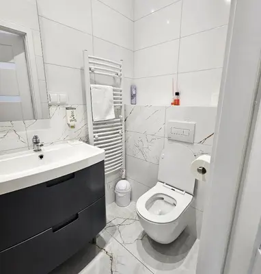 a white bathroom with a toilet and a sink at Juwel Apartments z widokiem na Wawel 32 in Kraków