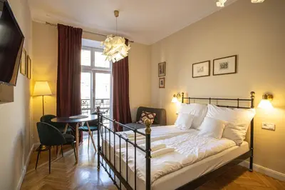 a bedroom with a bed and a table and a window at Plac Matejki Apartments by Noah in Kraków