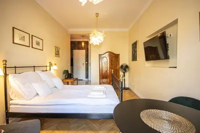 a bedroom with a bed with white sheets and a table at Plac Matejki Apartments by Noah in Kraków