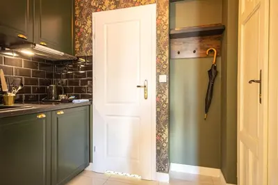 a kitchen with green cabinets and a white door at Plac Matejki Apartments by Noah in Kraków