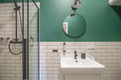 a green bathroom with a sink and a shower at Plac Matejki Apartments by Noah in Kraków