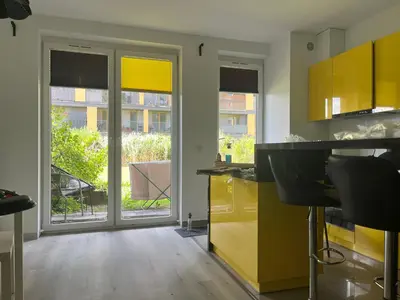 a kitchen with yellow cabinets and sliding glass doors at Apartament z ogrodem w Krakowie in Kraków