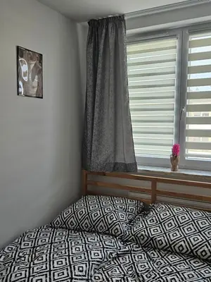 a bedroom with a bed and a window with a window curtain at Grey Apartment in Kraków