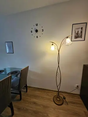 a lamp in a room with a table and a clock at Grey Apartment in Kraków