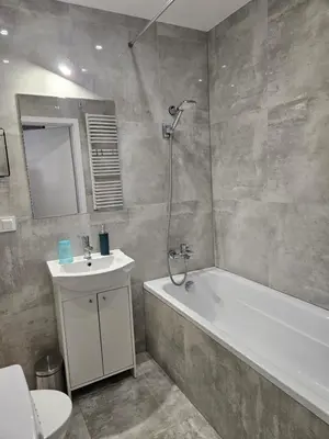 a bathroom with a tub and a sink and a shower at Grey Apartment in Kraków
