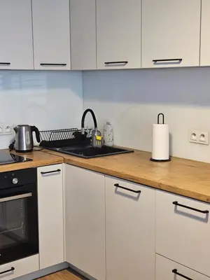 a kitchen with white cabinets and a stove top oven at Grey Apartment in Kraków