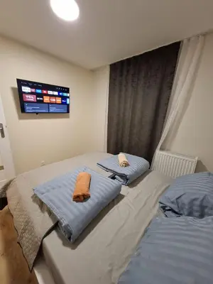 two twin beds in a bedroom with a tv on the wall at Apartament Rydlówka 39 in Kraków