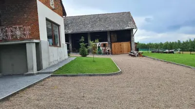 a house with a gravel driveway next to a building at Dom w zaciszu stodoły